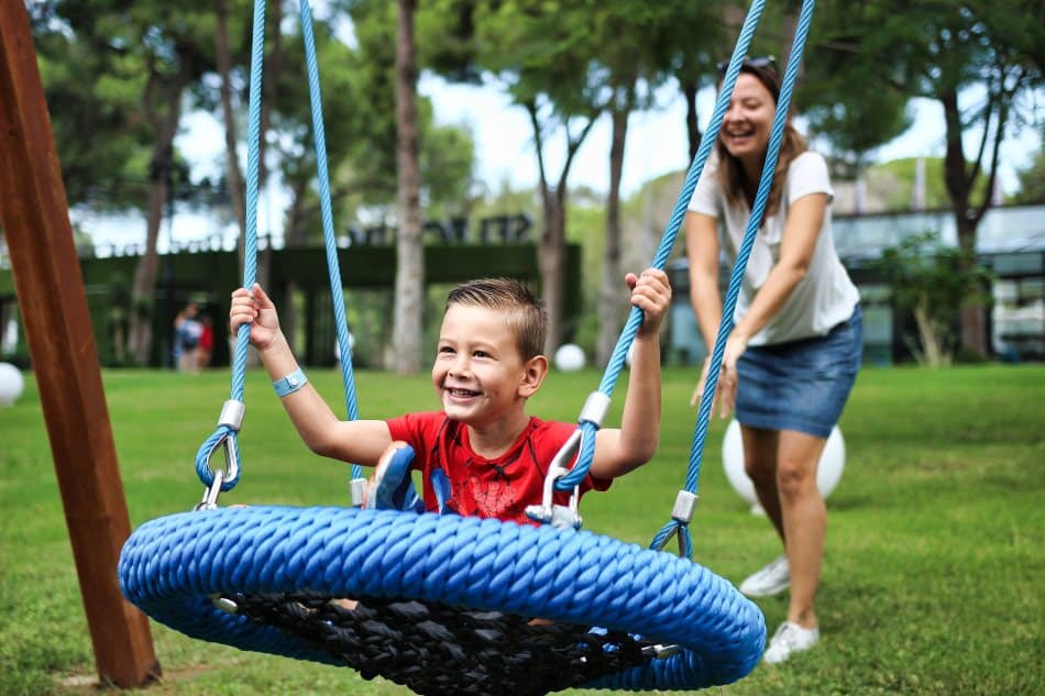 A kid having fun on a round swing. 