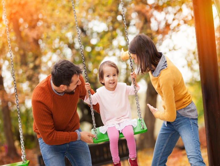 Family playing on the swing set. 