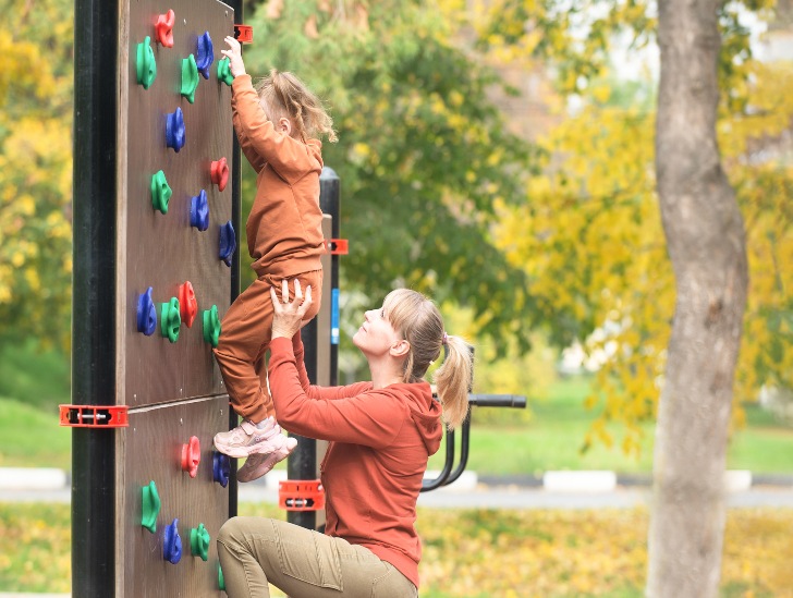 A mother guiding her daughter on climbing. 