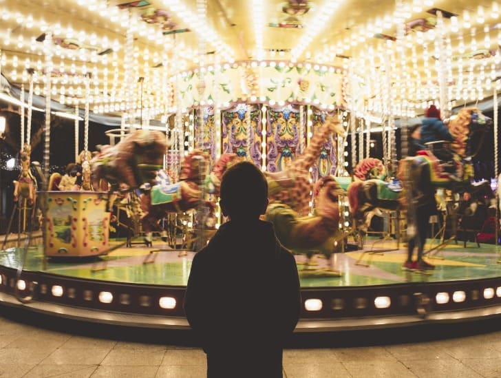  Boy standing infront of the merry go round. 