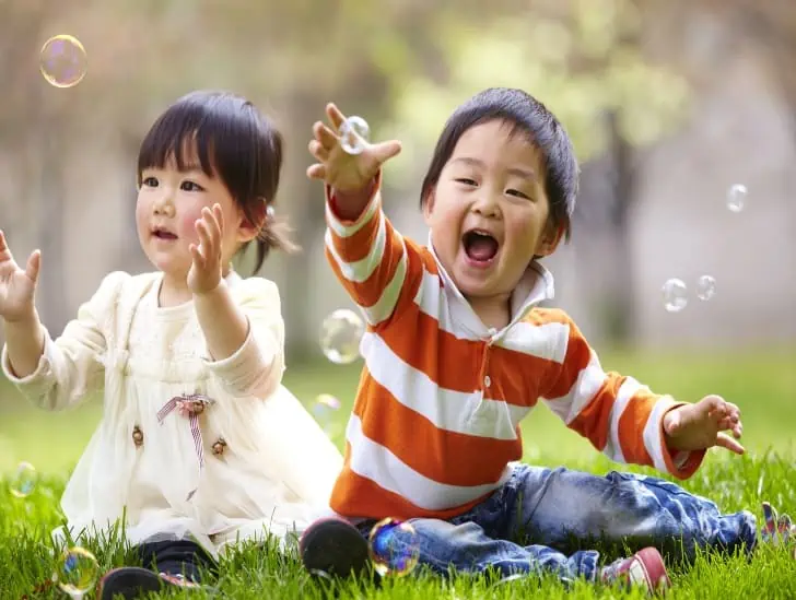 Toddlers outdoors playing with bubbles.