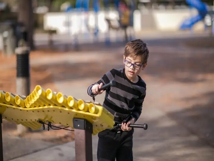 A boy playing on a musical instrument on playground